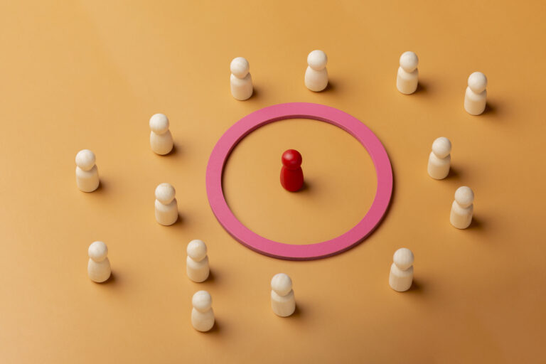 Imagem com bonecos brancos ao redor de um círculo rosa com um boneco vermelho