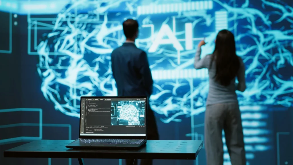 Inteligência artificial nas campanhas de marketing: um notebook na mesa, e ao fundo, duas pessoas trabalhando em fundo tecnológico