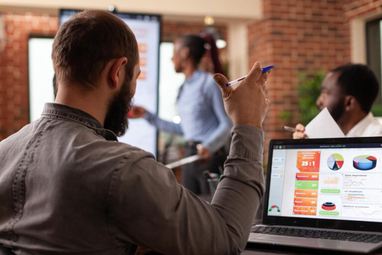 CRO para B2B: pessoas em escritório trabalhando; homem diante de um notebook com alguns gráficos.