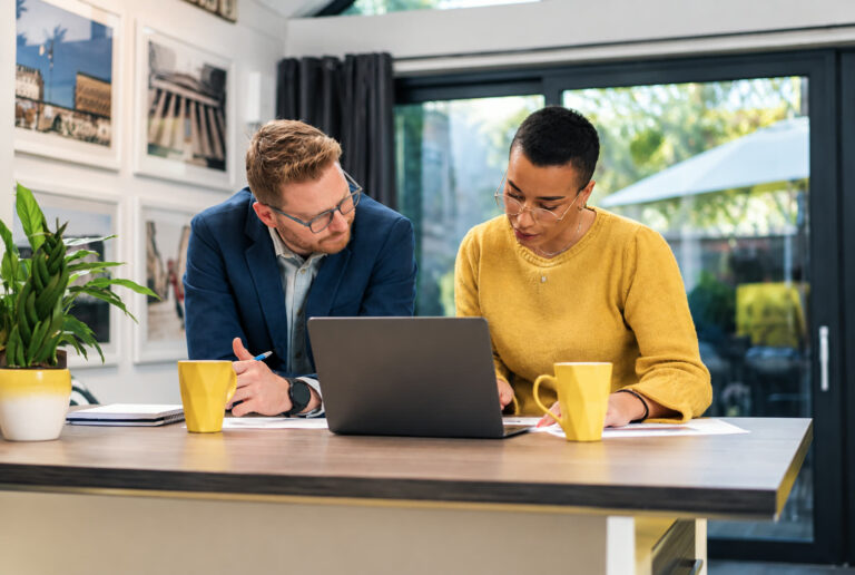 Quanto custa uma consultoria de marketing B2B: duas pessoas, um homem e uma mulher, analisando propostas em um notebook.