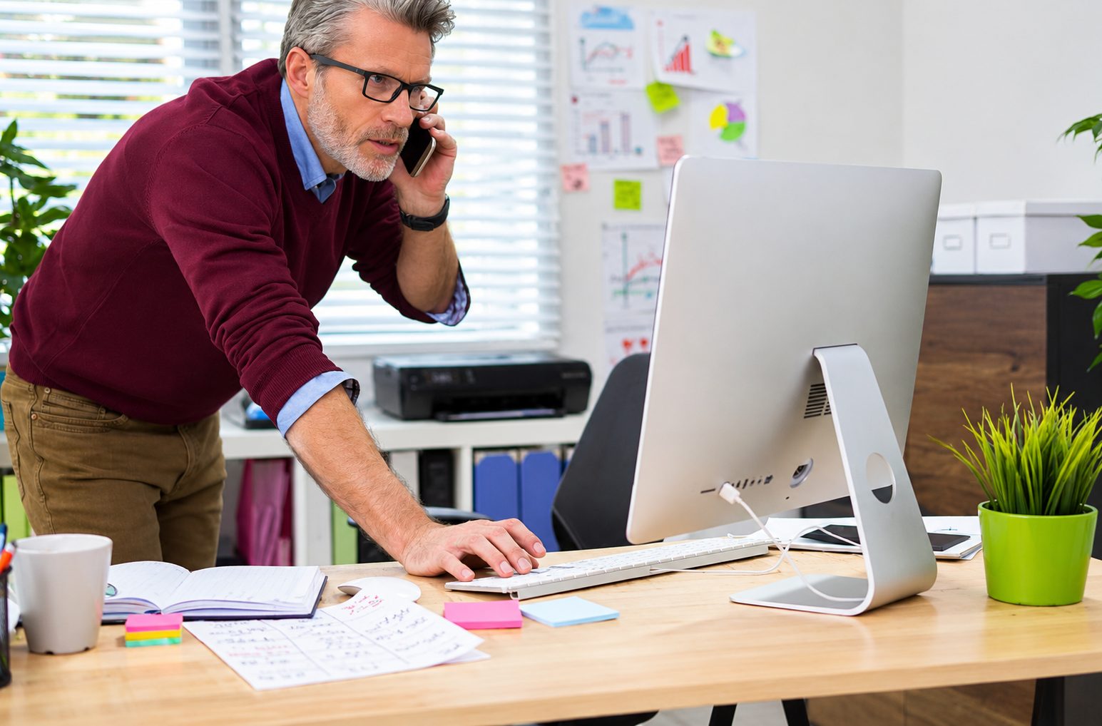 Decisor vs. influenciador no marketing B2B: por que seu conteúdo pode estar mirando a pessoa errada 1 Decisor vs influenciador no marketing B2B: empresário em escritório, falando ao celular e usando computador.